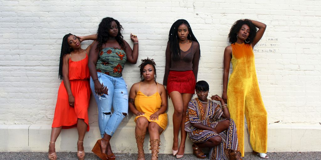 six women leaning on white wall