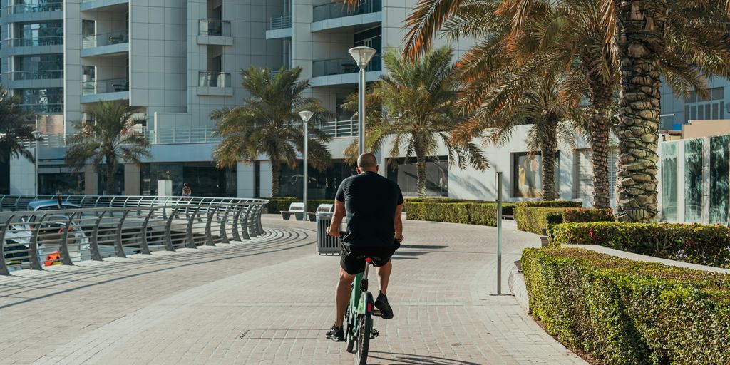 A man riding a bike down a street next to tall buildings