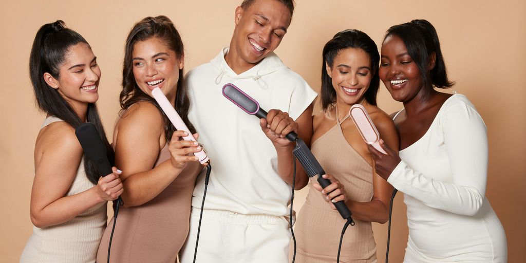 a group of women standing next to each other holding hairdryers